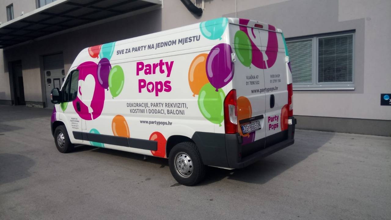 Vehicle wrap design for the company Party Pops from Zagreb, Croatia. The picture shows a colorfully painted van. In the center is the Party pops company logo, a magenta circle with a white heart-shaped balloon inside. The logo is surrounded by other balloons in various colors and on the side you can see the text Party Pops with their slogan and basic information.
