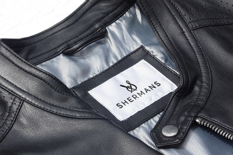 Na slici je prikazana ušivena etiketa na jakni modne marke Shermans.