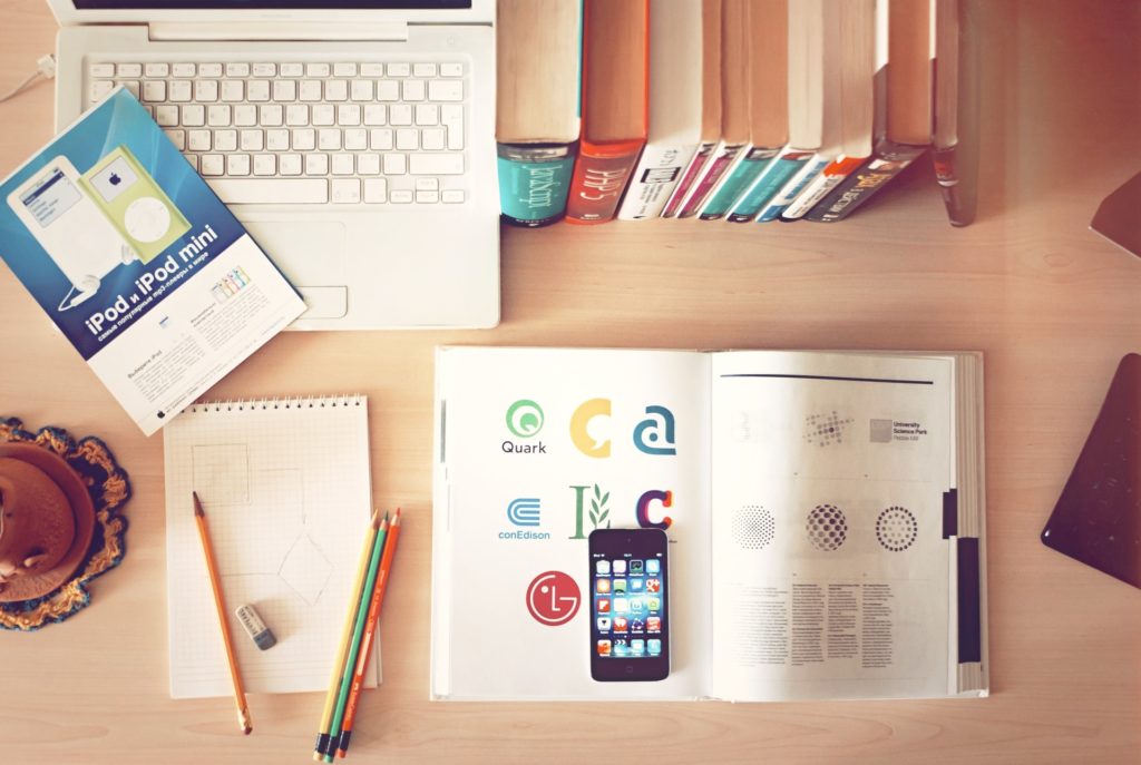 Types of logo. Image Credit: Aleks Dorohovich. In the picture there is a desk with a laptop, books, mobile phone, pens and a notebook.