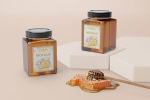 Dizajn etikete za pakiranje meda. Na slici su dvije staklenke meda s dizajniranim etiketama na njima. Nalaze se na bež površini.
