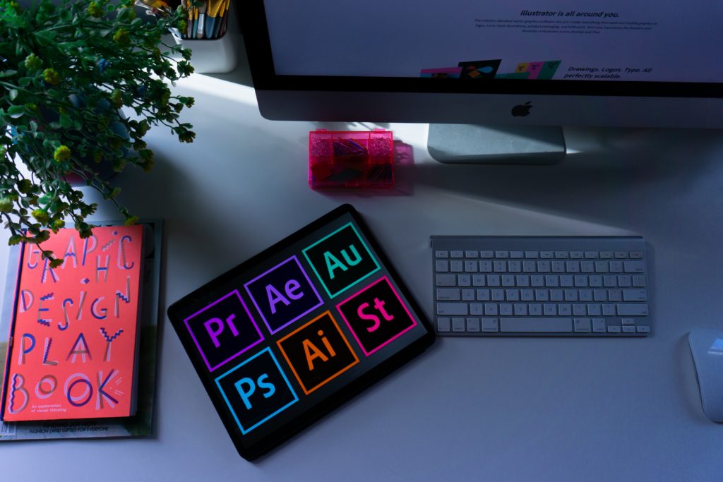 Blog about graphic design: the picture shows a desk with a tablet on which Adobe programs are open