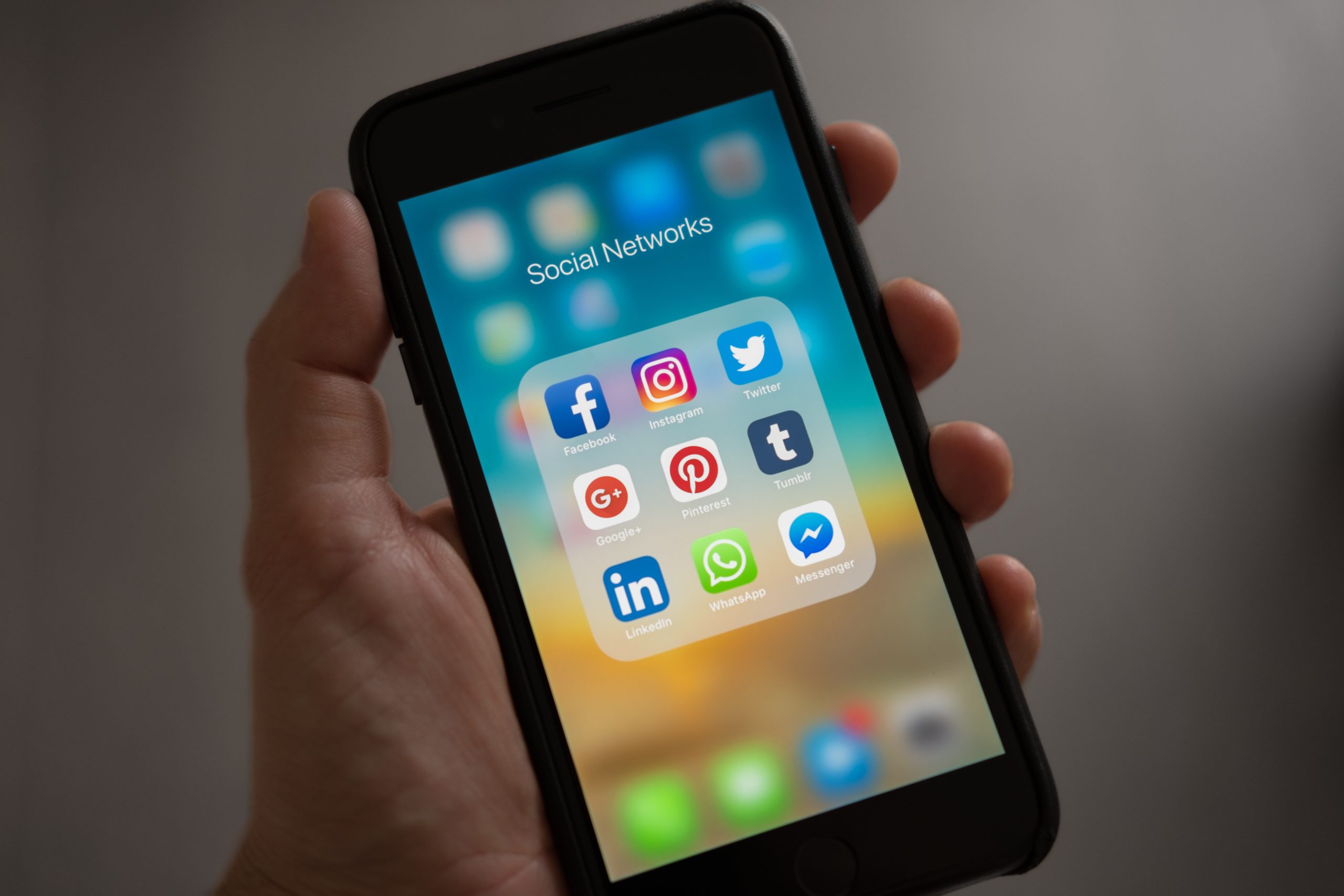 Blog o motion graphics: Na slici ruka drži mobilni uređaj sa otvorenim ekranom na kojemu su ikone najpoznatijih društvenih mreža. 
