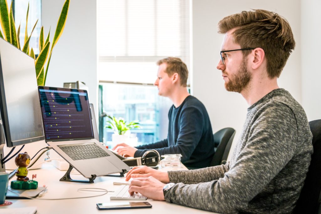 Blog o grafičkom dizajnu: slika prikazuje ured sa dva muška radnika kako rade za svojim računalima