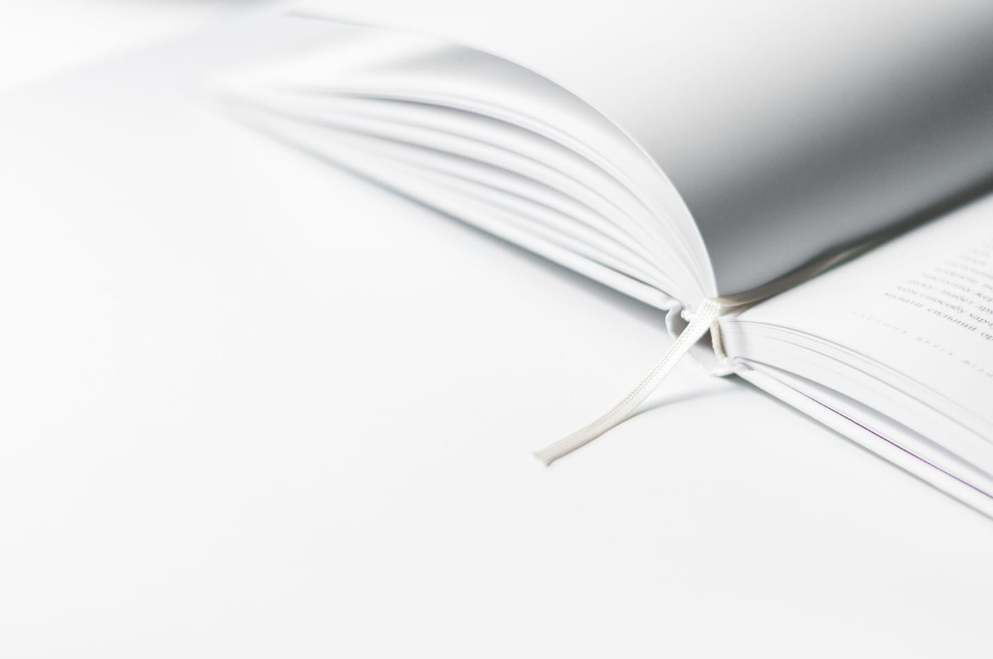 Open white book with a ribbon bookmark on a white surface