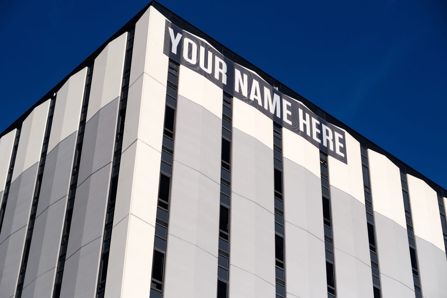White building facade with a “Your name here” sign against a deep blue sky
