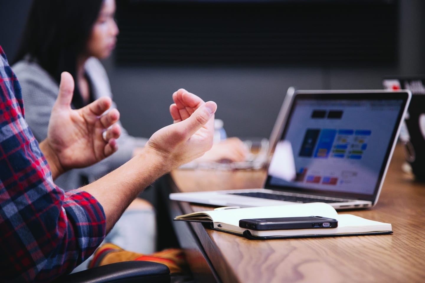 A meeting participant gesturing next to an open laptop