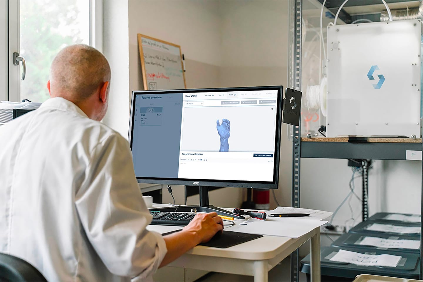 A specialist in a white coat working on a 3D model at a computer