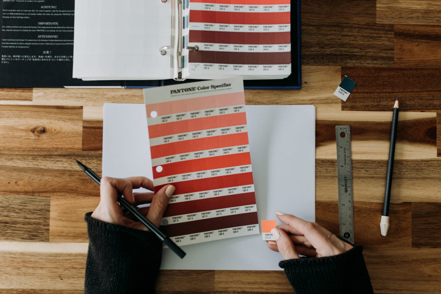 Logo and colors blog: the image shows a desk and hands holding a pantone color palette in shades of red.
