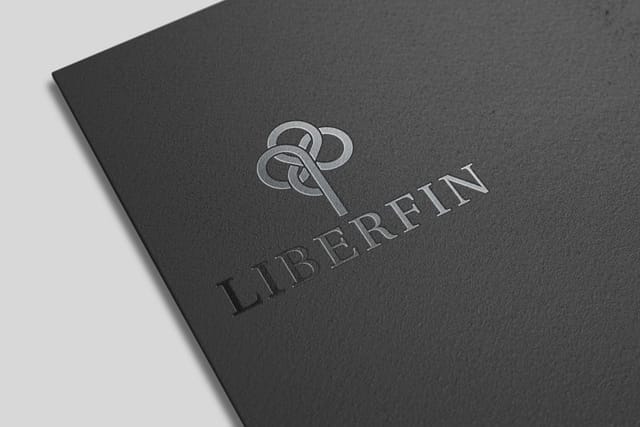 Corner of a black business folder on a white background, with the Liberfin logo printed in glossy black