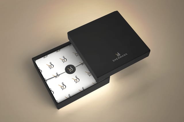 Packaging design for the fashion brand Shermans: a black clothing box with the logo, containing white tissue paper printed with a logo pattern