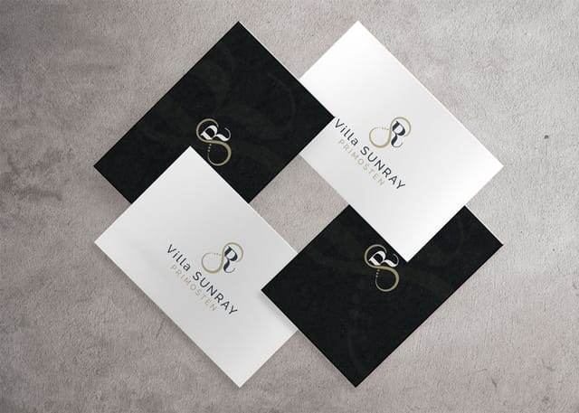 Business card design for Villa Sunray apartments: four business cards, two black and two white, arranged in a square on a concrete surface, all with the Villa Sunray logo