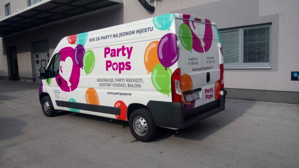 Party Pops van wrap, seen from the side and rear: a magenta circle with a white heart-shaped balloon, colourful balloons and the Party Pops name with the slogan and contact details