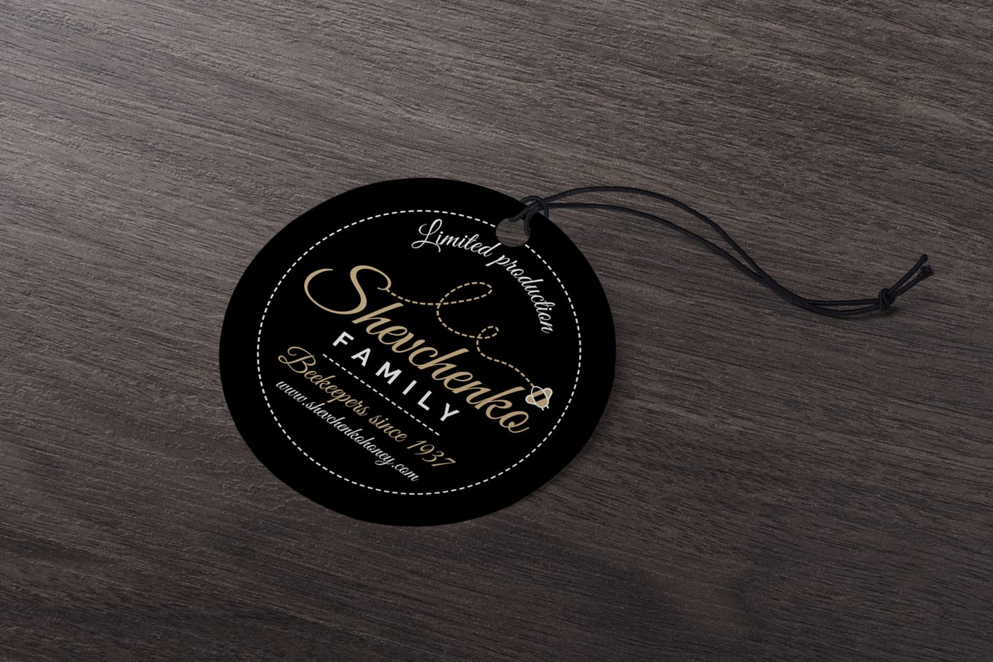 Shevchenko honey tag design: a round black hang tag with gold and white lettering and icons on a wooden table